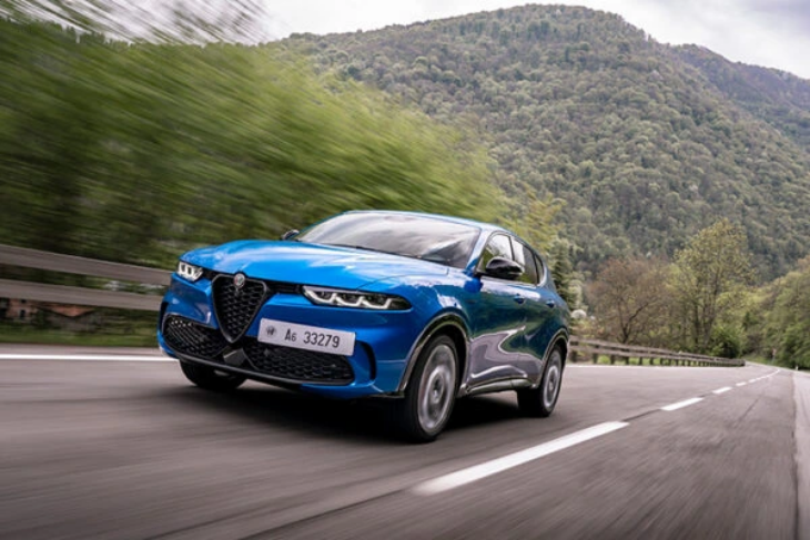 Mavi Alfa Romeo Tonale SUV, dağ manzaralı yolda sürüş halinde sportif ve dinamik tasarımıyla öne çıkıyor.