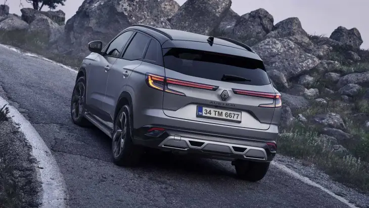 Gri Renault Austral SUV, kayalık dağ yolunda arka açıdan sürüş halinde güçlü ve modern tasarımıyla öne çıkıyor.