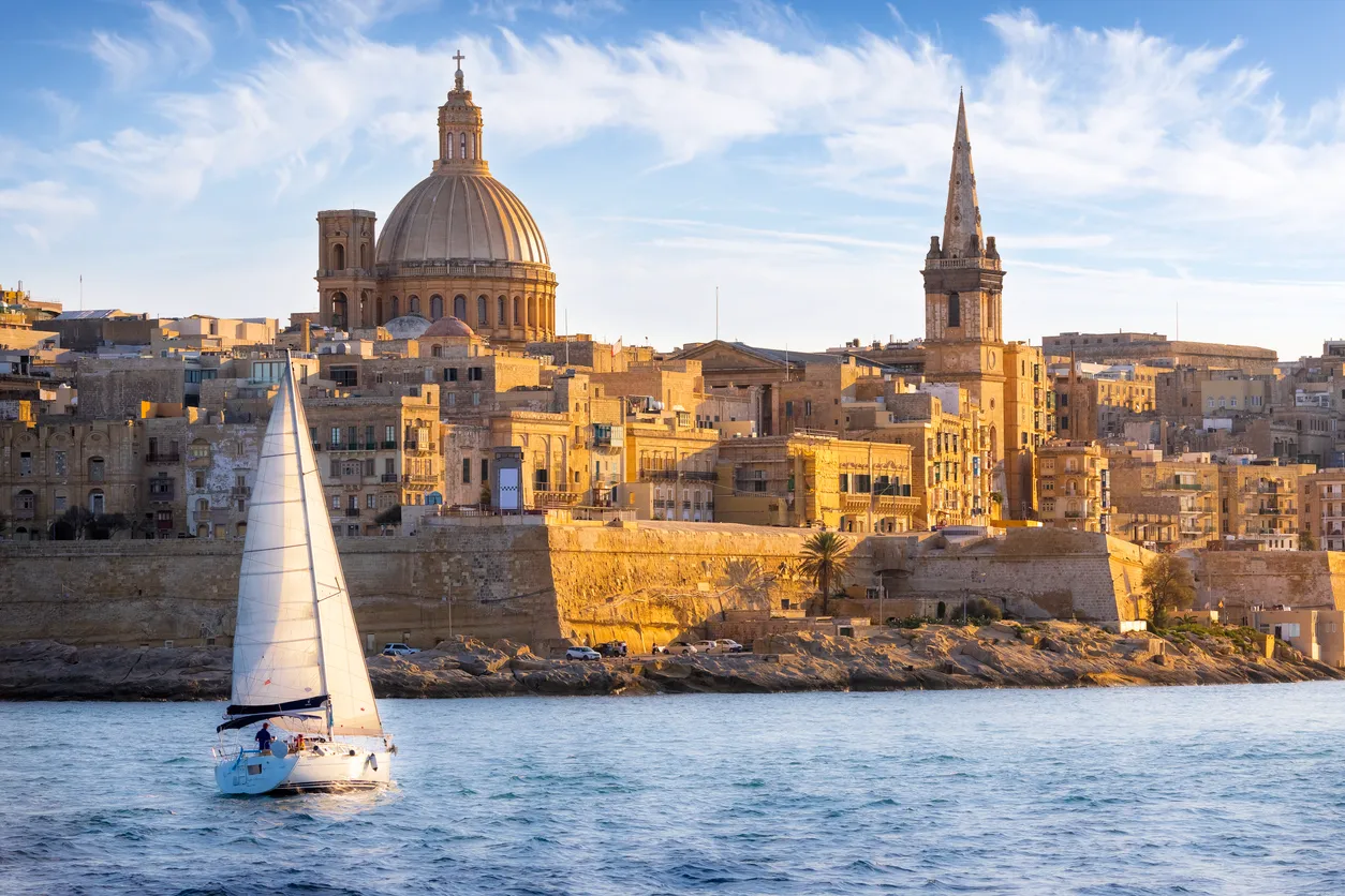 Malta’nın başkenti Valletta’da tarihi şehir silueti, kubbeli yapılar ve Akdeniz’de yelkenli tekne