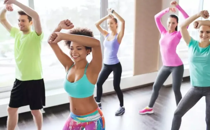 Renkli spor kıyafetleriyle Zumba yapan grup; latin ritimleriyle yüksek tempolu kalori yaktıran Zumba antrenmanı.