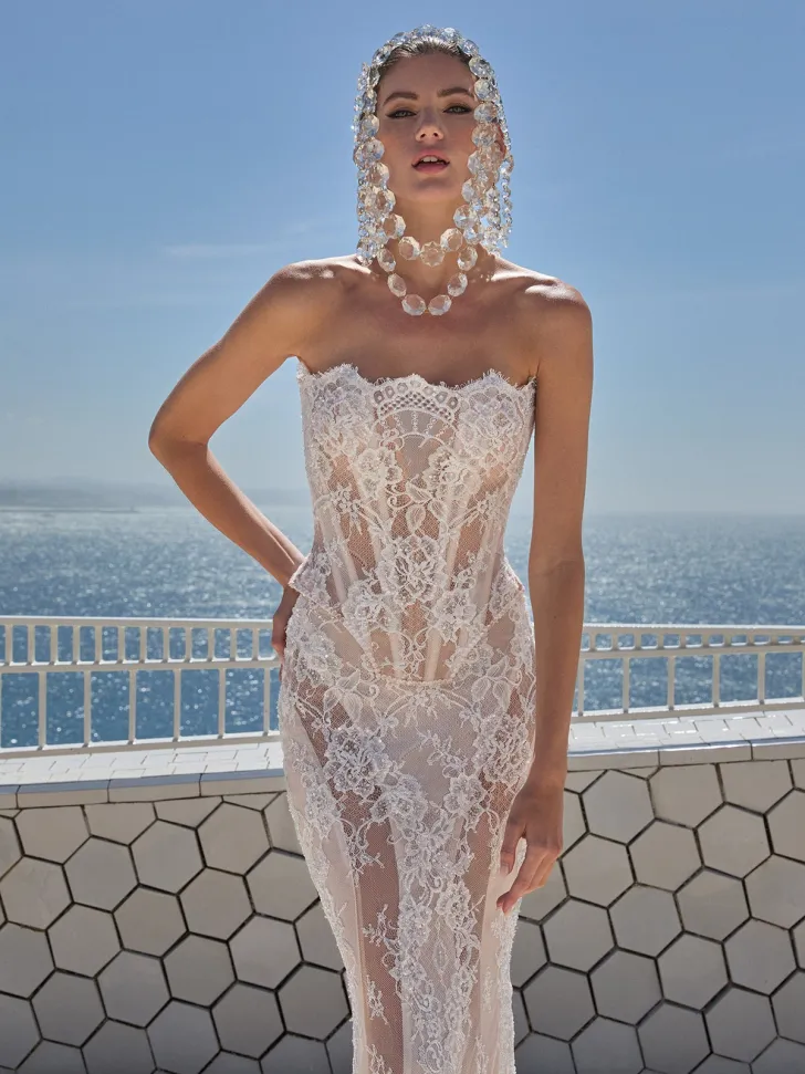 Deniz manzarası önünde poz veren model, transparan dantel kumaştan straplez bir Galia Lahav gelinlik ve iri taşlardan oluşan gösterişli bir başlık takıyor.