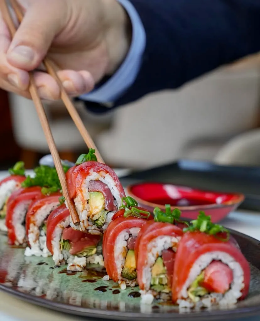 Bir el, ince ahşap çubuklarla, dışı taze kırmızı ton balığı ile sarılmış, içinde avokado ve pirincin eşlik ettiği, yeşilliklerle süslenmiş parlak bir sushi rulosunu zeytin yeşili bir tabaktan alırken, İstanbul'un en iyi sushi restoranlarındaki taze deniz mahsullerinin ve Uzak Doğu mutfağının rafine lezzetlerini vurgulayan iştah açıcı bir anı gözler önüne seriyor.