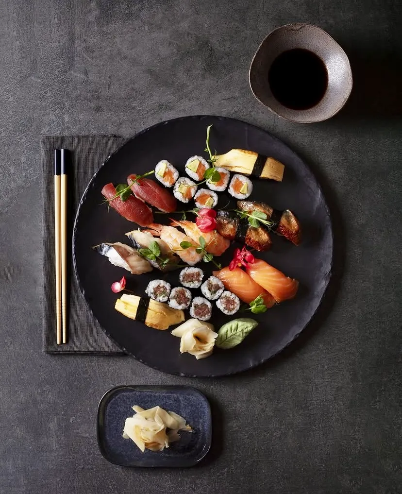 İstanbul'un en popüler sushi restoranlarından birinde sunulan, taze balık ve pirinçle özenle hazırlanmış; somon, orkinos ve karides nigiri, zarif roll çeşitleri, yılan balığı, tamagoyaki ve taze yeşilliklerle bezenmiş, koyu renk şık bir sunum tabağındaki Uzak Doğu mutfağı seçkisi.