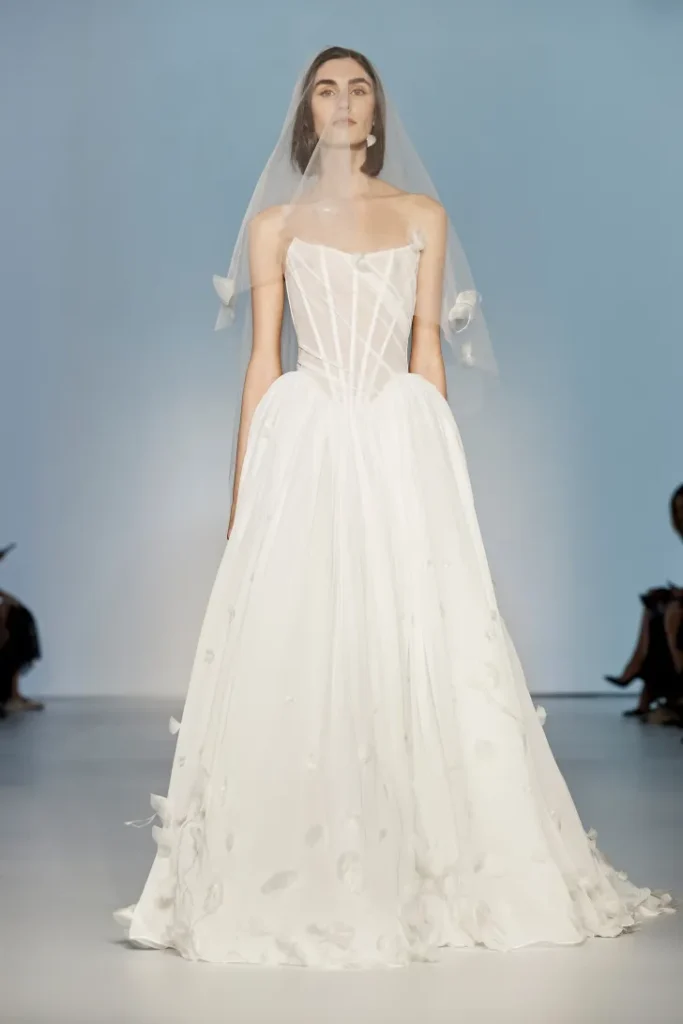 KYHA Studios tasarımı korse üst detaylı, düşük bel, A kesim gelinlik; hafif aplikeler ve duvakla tamamlanmış modern bridal look.