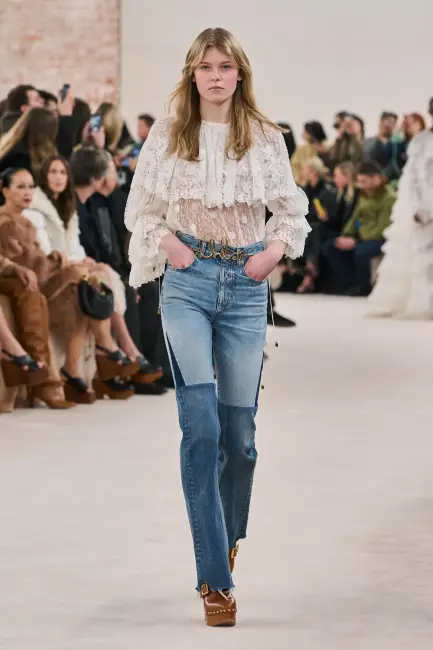 Podyumda, yama detaylı kot pantolonu, şeffaf dantelli bluzu ve Chloe imzalı kemeriyle yürüyen model, özellikle yaratıcı sektörlerde kurumsal hayatta rahatlığından ödün vermeden etkili giyimin ve özgün bir stil oluşturmanın mümkün olduğunu gösteriyor.
