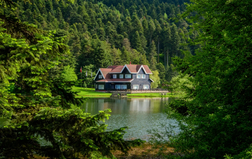 Abant Gölü kıyısında ormanlarla çevrili manzarada göl evi ve yansıması.