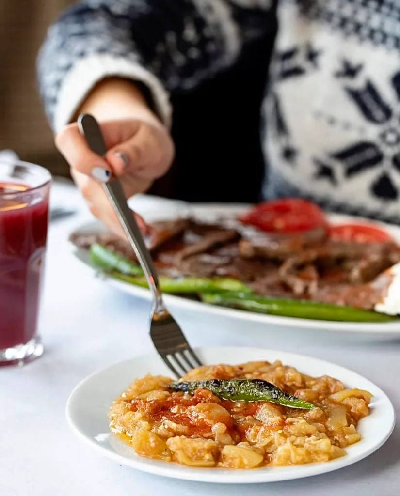 Mavi Dükkan Kebapçı İskender’de servis edilen köz patlıcan meze ve arka planda İskender kebap tabağı