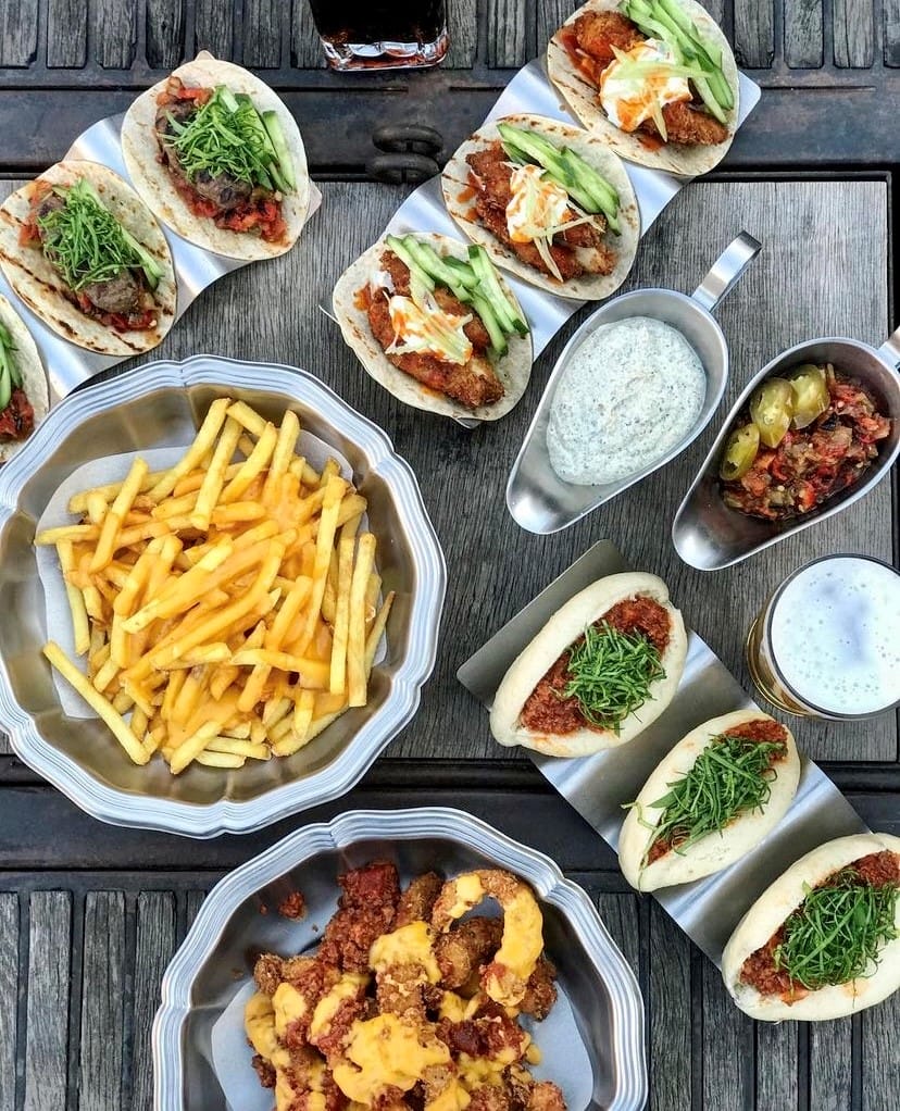 Bir ahşap masa üzerinde servis edilen, Etiler ve Akatlar'ın gözde sokak lezzetlerinden Dirty Hands restoranına özgü bol malzemeli tavuklu ve dana etli tacolar, yeşillikli bao sandviçler, peynirli patates kızartması ve çıtır tavuk parçalarından oluşan iştah açıcı bir ziyafet sofrası, burayı gurmelerin radarında tutan bir lezzet durağı olduğunu kanıtlıyor.