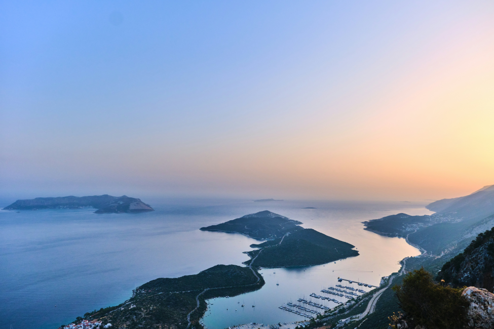 Kaş’ta sonbahar gün batımında deniz manzarası ve adalarla çevrili huzurlu bir sahil görünümü.