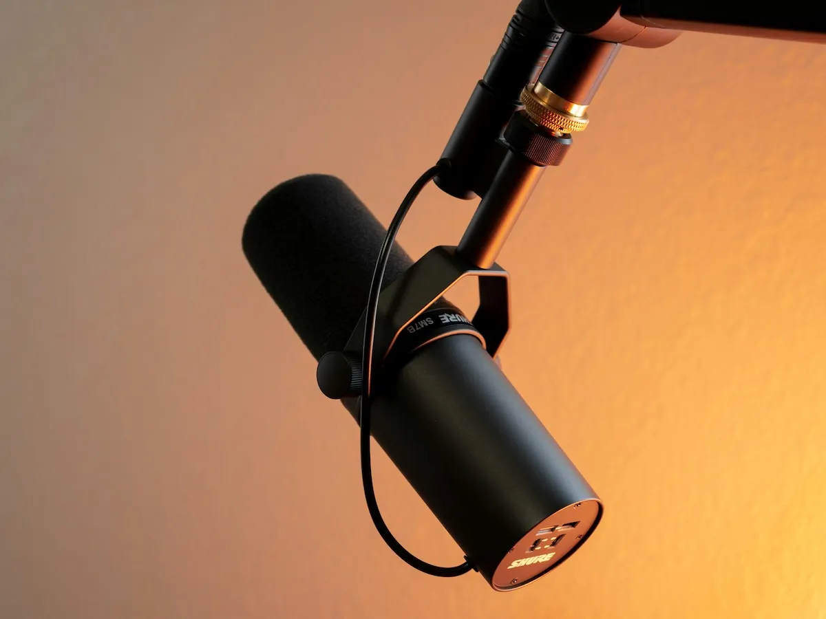 Büyük bir stüdyo mikrofonu ve kulaklık takmış, yüzünde neşeli bir ifadeyle konuşan sakallı bir adam, komedi podcastleri üzerine hazırlanan bu makaleyi en iyi şekilde yansıtan anı kaydediyor.