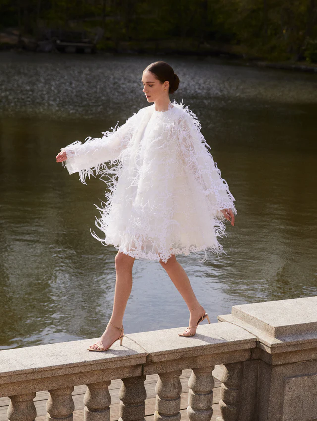 Oscar de la Renta tasarımı, tamamen tüy aplikeleriyle bezenmiş kısa gelinlik modeli. Eğlenceli, hacimli ve zarif siluetiyle nikah sonrası parti ya da bridal shower için göz alıcı bir seçenek sunuyor.