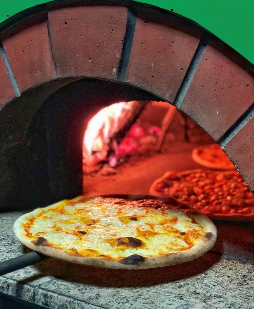 Geleneksel taş fırından yeni çıkmış, kenarları hafifçe kararmış, üzerinde erimiş peyniri kabarcıklar oluşturan lezzetli bir pizza, arkasında fırında pişmeye devam eden diğer pizzalarla birlikte, Etiler ve Akatlar'ın en iyi mekanlarında sunulan nefis tatlardan birine işaret ediyor.