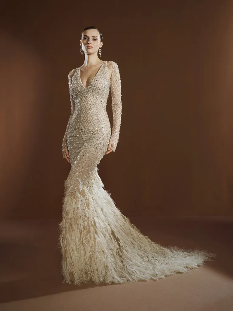 Pronovias imzalı, tamamı inci ve payet işlemeli, derin V yaka ve uzun kollu, eteği tüy detaylı balık formunda gelinlik modeli.