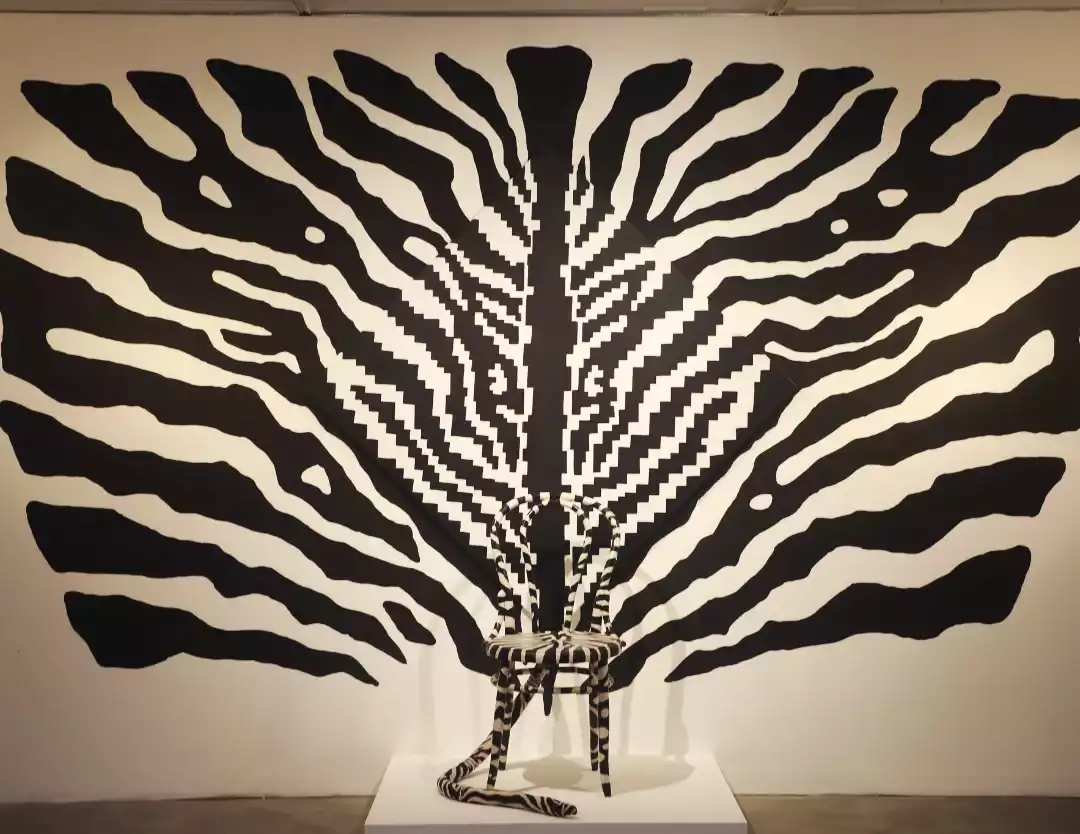 Buenos Aires'in kültürel zenginliklerini ve modern sanat sahnesini yansıtan bu etkileyici enstalasyon, siyah beyaz dalgalı çizgilerin pikselli bir merkezle birleştiği büyük bir duvar sanatı ve önündeki uyumlu çizgili sandalyeyi içeriyor.