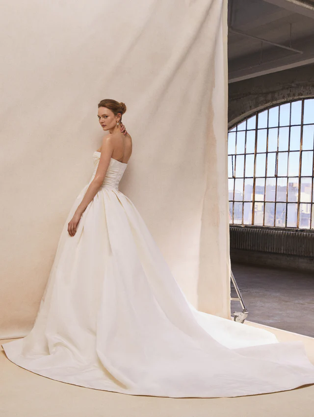 Oscar de la Renta 2026 koleksiyonundan, sade straplez yaka ve uzun kuyruk detaylı klasik gelinlik modeli.