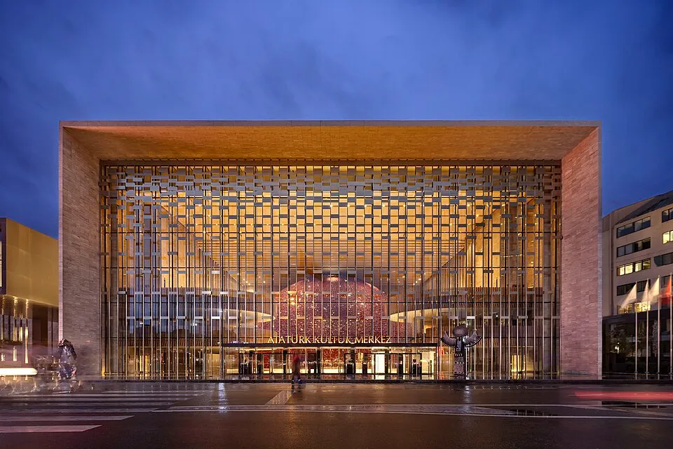 Taksim'deki modern Atatürk Kültür Merkezi'nin (AKM) akşam aydınlatmasıyla ışıldayan ön cephesi, geometrik desenli cam giydirmesinin ardında yükselen ikonik kırmızı opera salonu küresiyle dikkat çekiyor.