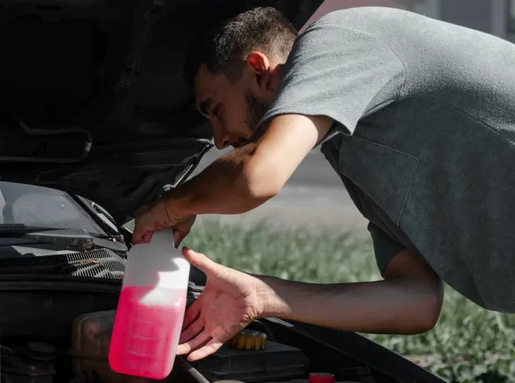 Bir kişinin aracına kırmızı antifriz eklemesi; motor soğutma sistemi ve kışlık araç bakımı hazırlığı
