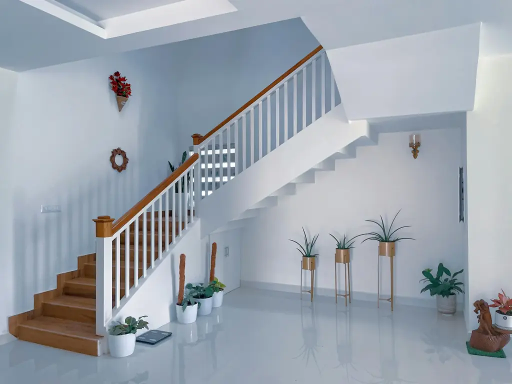 Merdiven altı dekorasyonu, beyaz saksılarda yeşil bitkiler, ahşap detaylı modern merdiven tasarımı ve minimalist iç mekân düzeni