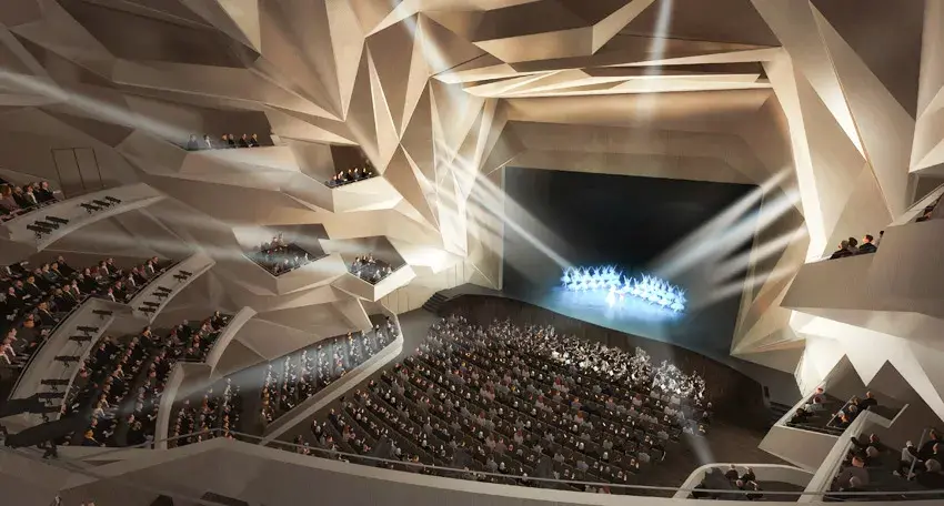 Rabat Kraliyet Tiyatrosu'nun göz alıcı, geometrik hatlara sahip modern salonunda, ışıklarla aydınlatılmış sahnede performans sergileyen balerinler ve onları izleyen çok sayıda seyirci, çok katlı balkonlar ve ana oturma alanlarını doldurarak canlı bir gösteri atmosferi yaratıyor.