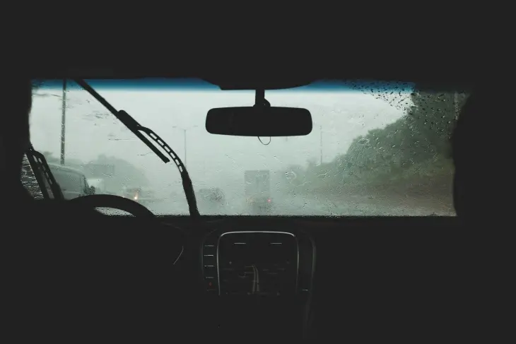 Yağmurlu havada çalışan silecekler ve araç içinden yol görünümü; kış sürüşünde görüş güvenliği ve silecek kontrolü
