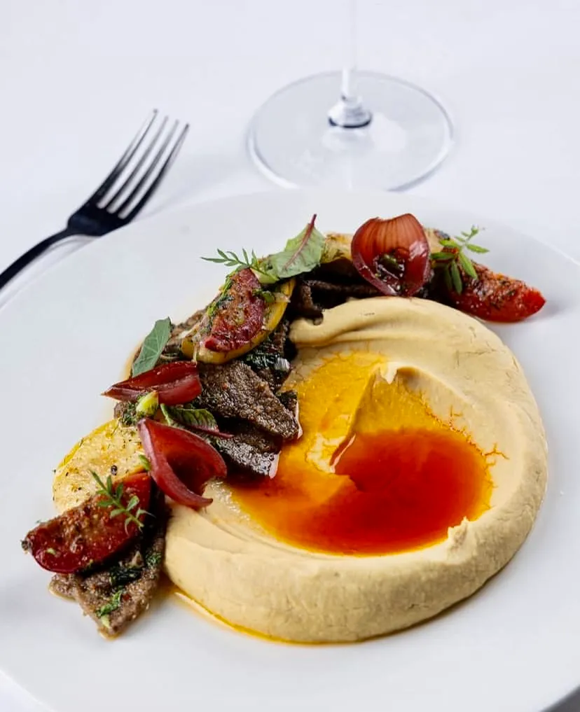 Beymen Brasserie’de humus üzerinde et ve közlenmiş sebze sunumu — Nişantaşı mekanları rehberinden.