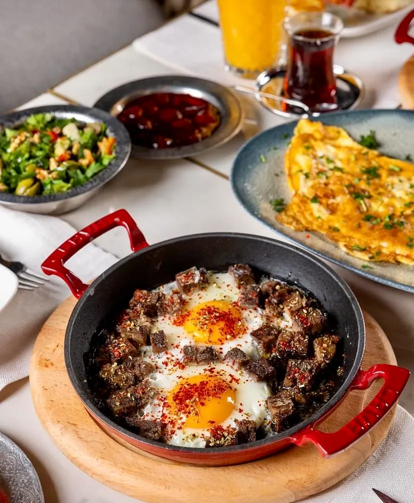 Develi Nişantaşı’nda kuzu ciğerli yumurta, omlet ve salata eşliğinde kahvaltı tabağı — Nişantaşı mekanları rehberinden.