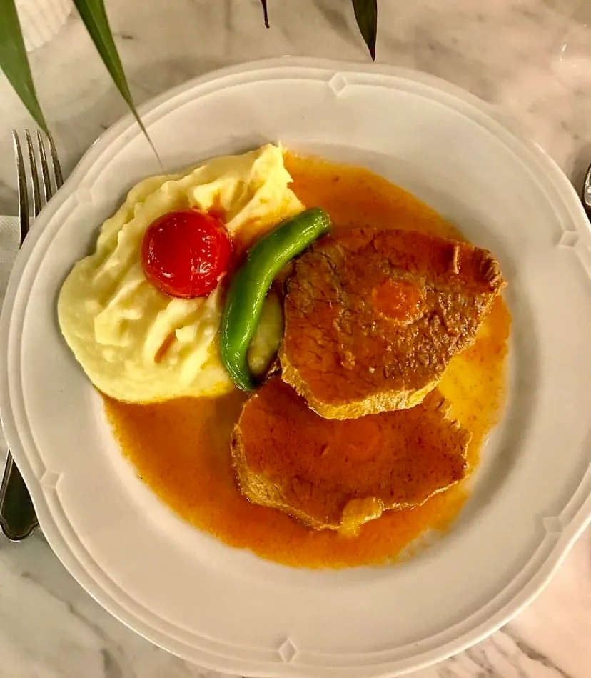Hünkâr Nişantaşı’nda patates püresi, domates ve biber eşliğinde sunulan et yemeğ — Nişantaşı mekanları rehberinden.