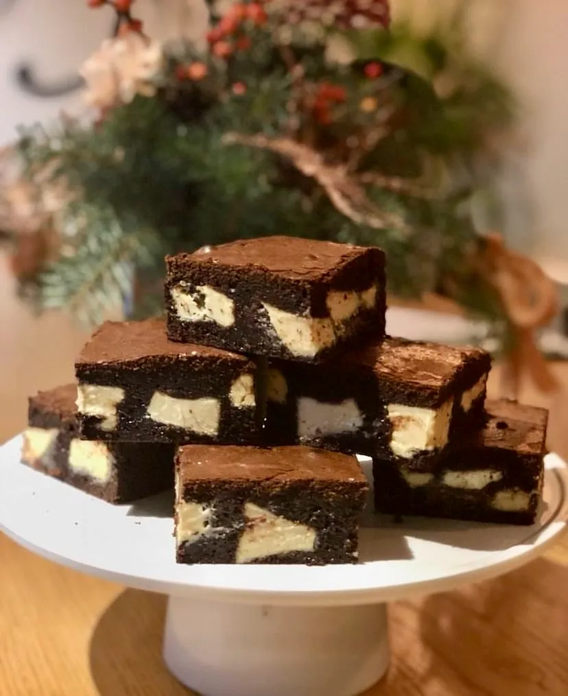 Kare dilimlenmiş yoğun çikolatalı ve beyaz dolgulu brownie tatlıları, servis tabağı üzerinde üst üste dizilmiş halde — Nişantaşı mekanları rehberinden.