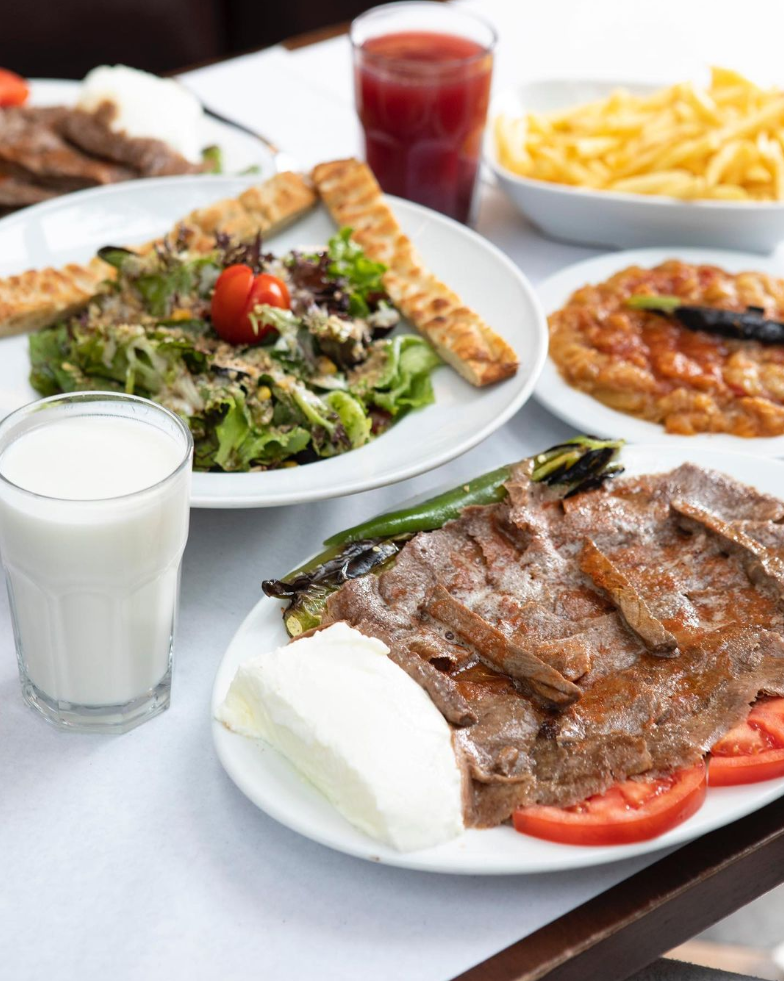 Kebapçı İskender Nişantaşı’nda yoğurtlu döner kebap, közlenmiş biber, salata, patates kızartması ve ayran servisi — Nişantaşı mekanları rehberinden.