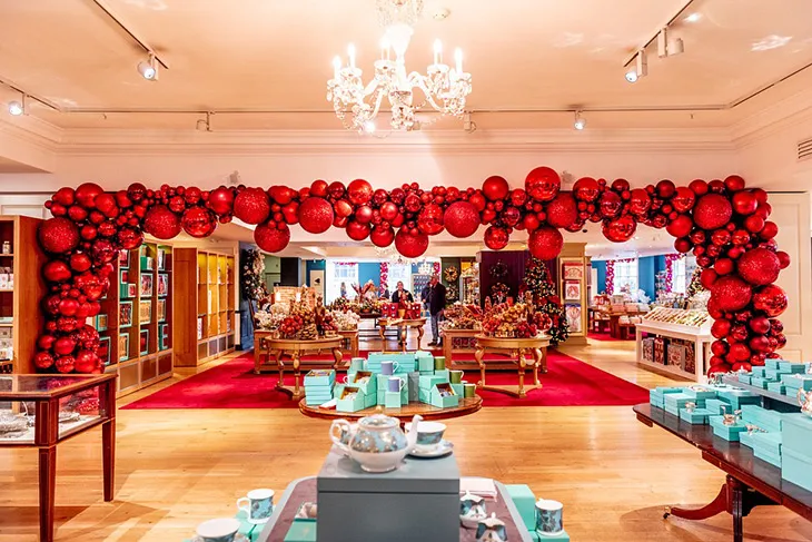 Fortnum & Mason mağazasında kırmızı yılbaşı süsleri, hediye paketleri ve zarif Noel dekorasyonlarıyla Londra’da şık yılbaşı alışverişi atmosferi.