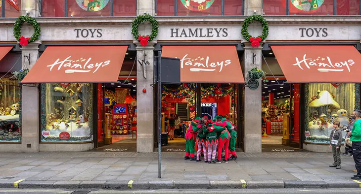 Hamleys oyuncak mağazası önünde Noel kostümlü elfler ve yılbaşı süslemeleriyle Londra’da festivite atmosferi.