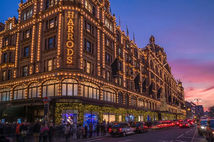 Harrods’un yılbaşı ışıklarıyla süslenmiş dış cephesi ve Noel alışverişi için sırada bekleyen kalabalık, Londra.