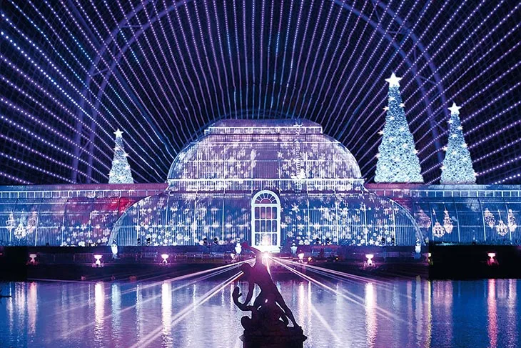 Kew Gardens’ın Christmas at Kew ışık gösterisi sırasında aydınlanan cam serası ve yılbaşı ağaçlarıyla büyüleyici Noel atmosferi.