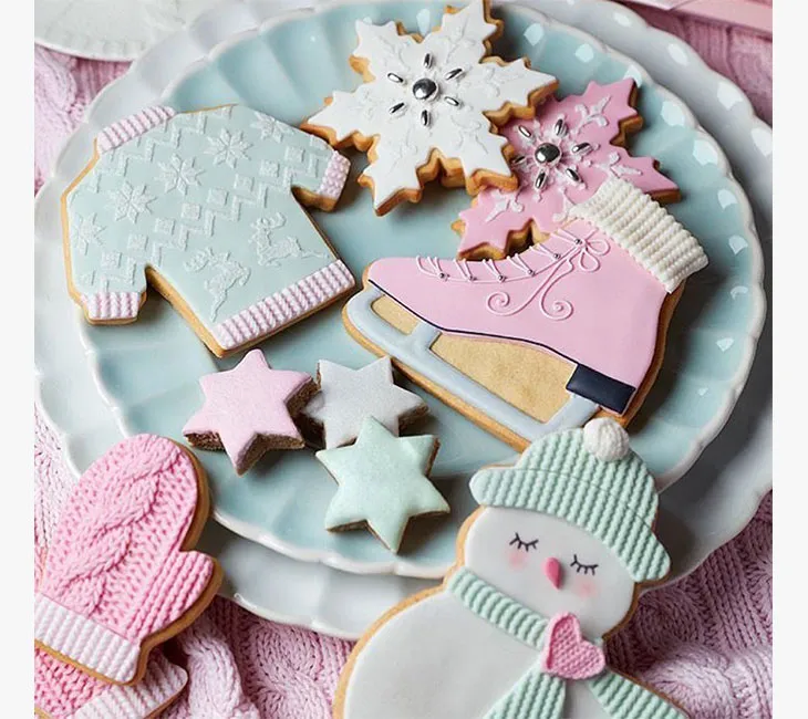 Pastel renklerde yılbaşı kurabiyeleri; buz pateni pisti pateni, kazak, yıldız ve kardan adam şeklinde süslü Noel tatlıları.