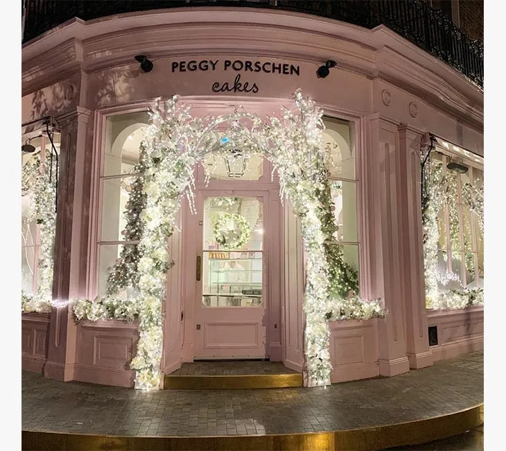 Peggy Porschen pastanesinin beyaz ışıklarla süslenmiş yılbaşı dekorasyonu ve pastel pembe cephesi, Londra.