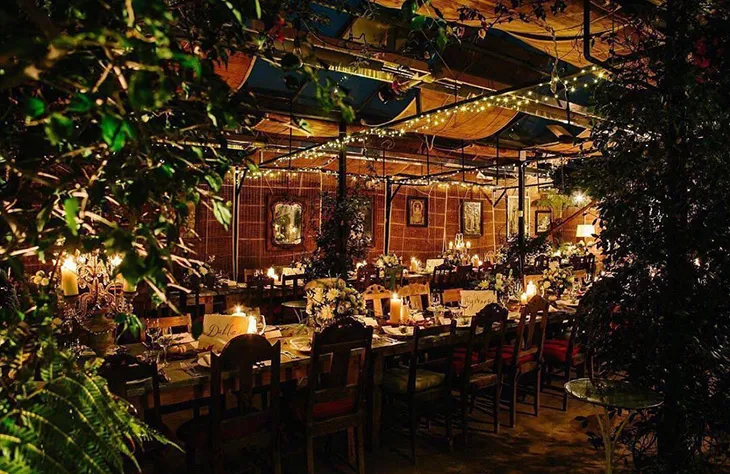 Petersham Nurseries’de mum ışıkları, bitkiler ve sıcak ışıklarla dekore edilmiş masalarda büyüleyici Noel akşamı atmosferi.