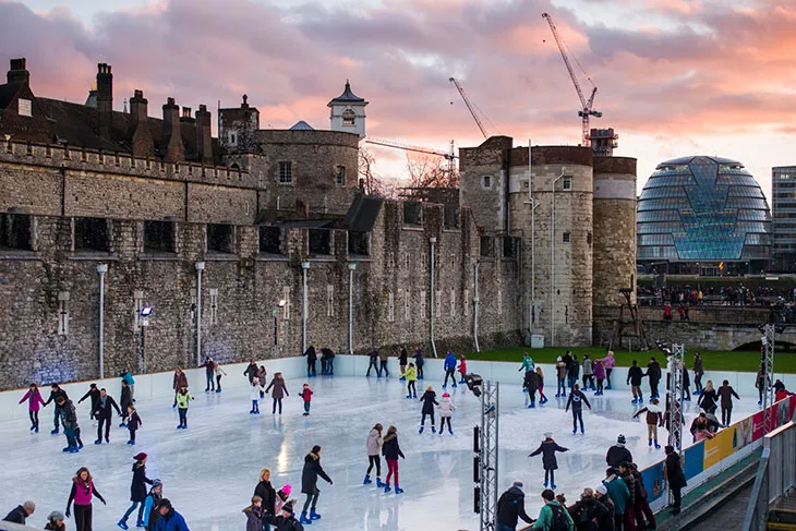 Tower of London yanında kurulan buz pistinde kayan insanlar ve gün batımı ışıklarıyla Londra’da kış ve Noel atmosferi.
