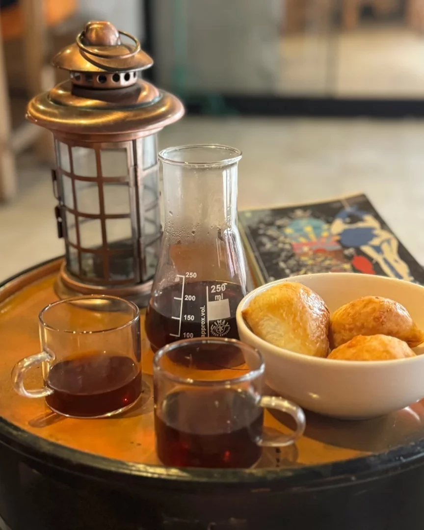 Cihangir'deki Mundo Novo'da bir masanın üzerinde, bakır renkli fenerin yanında, deney tüpünü andıran ölçülü bir cam beherde demlenmiş kahve ve iki küçük kulpsuz fincanla sunulan özel bir kahve servisi, taze kızarmış hamur işi (pişi) dolu beyaz bir kaseyle tamamlanıyor.