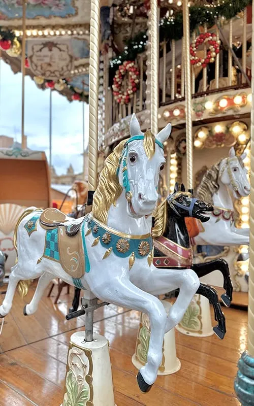 Strasbourg’da Alsace Noel Pazarları sırasında ışıklarla süslenmiş atlı karınca üzerindeki beyaz ve siyah at figürleri, detaylı Christmas dekorlarıyla birlikte.