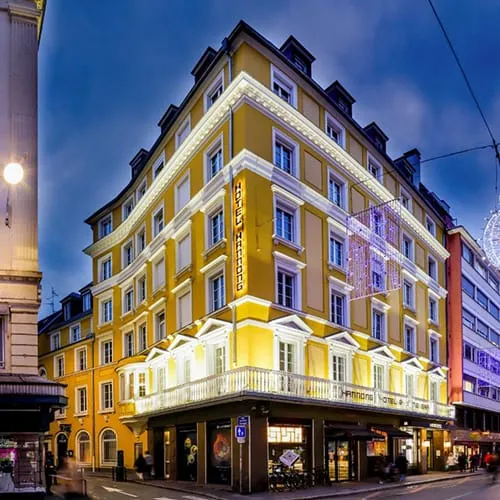 Strasbourg şehir merkezinde yer alan Hôtel Hannong’un sarı cephesi, gece aydınlatmaları ve klasik Avrupa mimarisiyle öne çıkan konaklama binası.