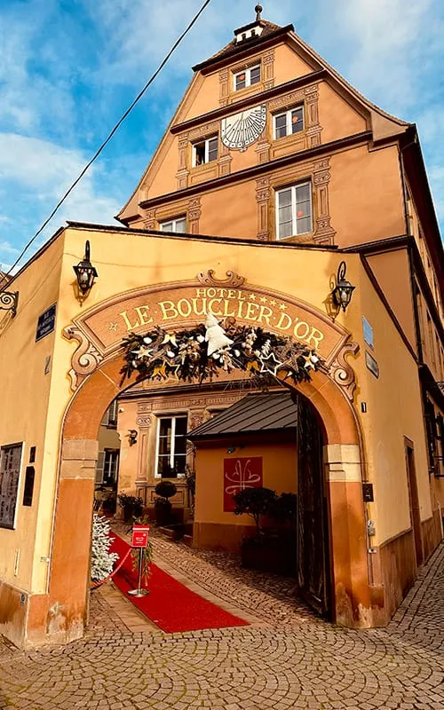 Strasbourg’daki tarihi Hotel Le Bouclier d’Or’un yılbaşı süslemeleriyle dekore edilmiş avlu girişi ve geleneksel Alsace mimarisi.
