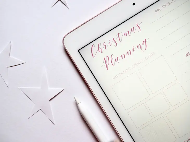 Yeni yıl planlaması yapılan tablet ekranı ve yıldız süslemeleriyle oluşturulmuş minimal hedef belirleme teması.