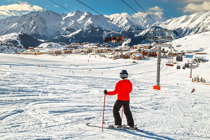 Fransa’daki Alpe d’Huez kayak merkezinde mavi ve yeşil pistlerde kayan bir kayakçı