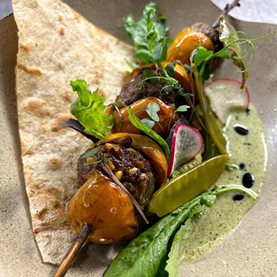 Araka restoranından, İstanbul’un Michelin Yıldızlı Restoranları listesinde yer alan, taze yeşillikler, turp dilimleri ve yeşil sosla zenginleştirilmiş, şişe dizili, karamelize minik armutlar veya ayvalar ile et köftelerinin lavaş üzerinde sunulduğu yaratıcı ve özenli bir lezzet sunumu.