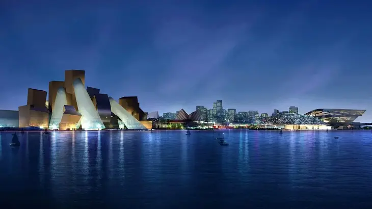 Abu Dhabi'nin sakin sularının karşısından çekilmiş bu etkileyici gece görüntüsünde, Frank Gehry'nin imzasını taşıyan Guggenheim Abu Dhabi Müzesi, karmaşık geometrik formları ve farklı açılardan yansıyan ışıklarıyla modern mimarinin doruk noktası olduğunu kanıtlarcasına parlıyor.