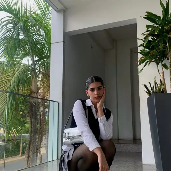 Beyaz gömlek ve siyah yelek kombiniyle modern bir ofis tarzı, siyah çorap ve mini etekle tamamlanmış görünüm