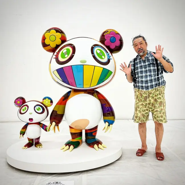 Takashi Murakami, kendi tasarımı olan dev renkli panda heykelleriyle birlikte poz veriyor. Sanatçının karakteristik figürleri, Japon pop kültüründen ilham alıyor.