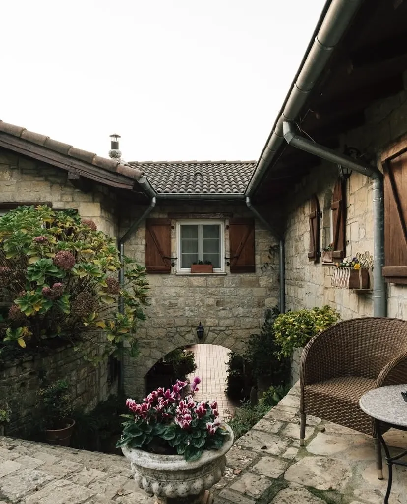 Casa Lavanda Şile’nin taş duvarlı avlusu, ahşap kepenkli pencereleri ve çiçeklerle süslenmiş huzurlu atmosferi