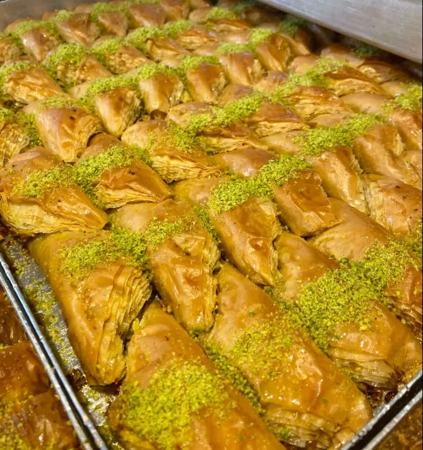 Büyük metal tepsiye dizilen, nar gibi kızarmış altın sarısı üçgen dilim baklavalar şerbetiyle parlıyor. İncecik katmanlı çıtır yufkaların üzerine bolca dökülen parlak yeşil Antep fıstığı tozu, geleneksel Türk tatlı kültürünü gözler
