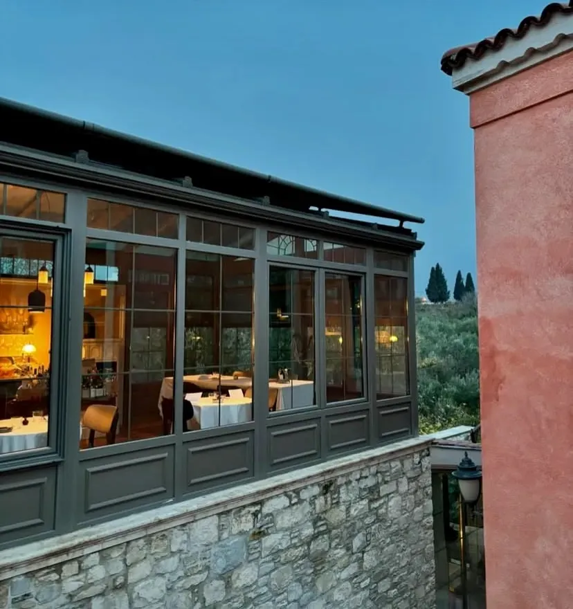 Narimor Urla Otel restoranının taş duvarlı dış cephesi ve camlarla çevrili şık yemek alanı, akşam atmosferiyle birlikte
